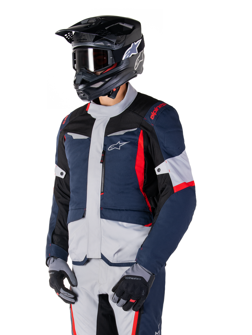 Giacca Alpinestars ST-1 Waterproof, giacca da moto adventure touring in blu scuro, nero e rosso acceso, indossata con un casco nero e guanti grigi, caratterizzata da un design moderno con tasche funzionali e marchio Alpinestars.