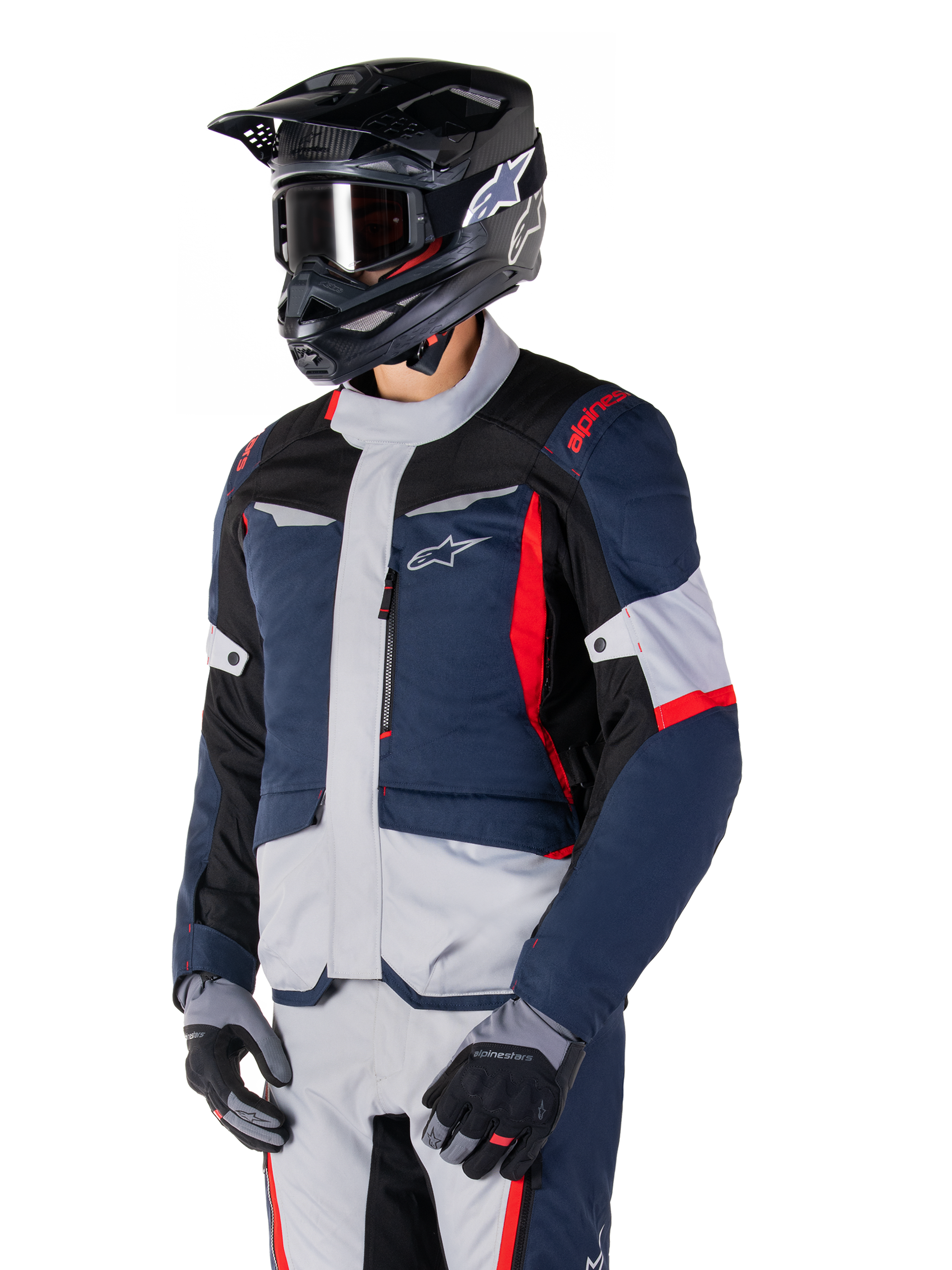 Giacca Alpinestars ST-1 Waterproof, giacca da moto adventure touring in blu scuro, nero e rosso acceso, indossata con un casco nero e guanti grigi, caratterizzata da un design moderno con tasche funzionali e marchio Alpinestars.