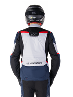 Giacca impermeabile Alpinestars ST-1, blu scuro, nero e rosso acceso, vista posteriore con pannello grigio chiaro e logo, giacca da moto adventure touring indossata con casco e guanti neri, design aerodinamico per ogni condizione atmosferica