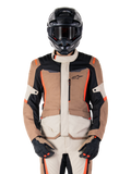 Giacca Alpinestars ST-1 Waterproof, Dark Khaki Sand Black Red Fluo, indossata da un pilota con casco e guanti neri, abbigliamento adventure touring con pannelli beige e marroni e vivaci accenti rosso fluo, vista frontale su sfondo bianco.