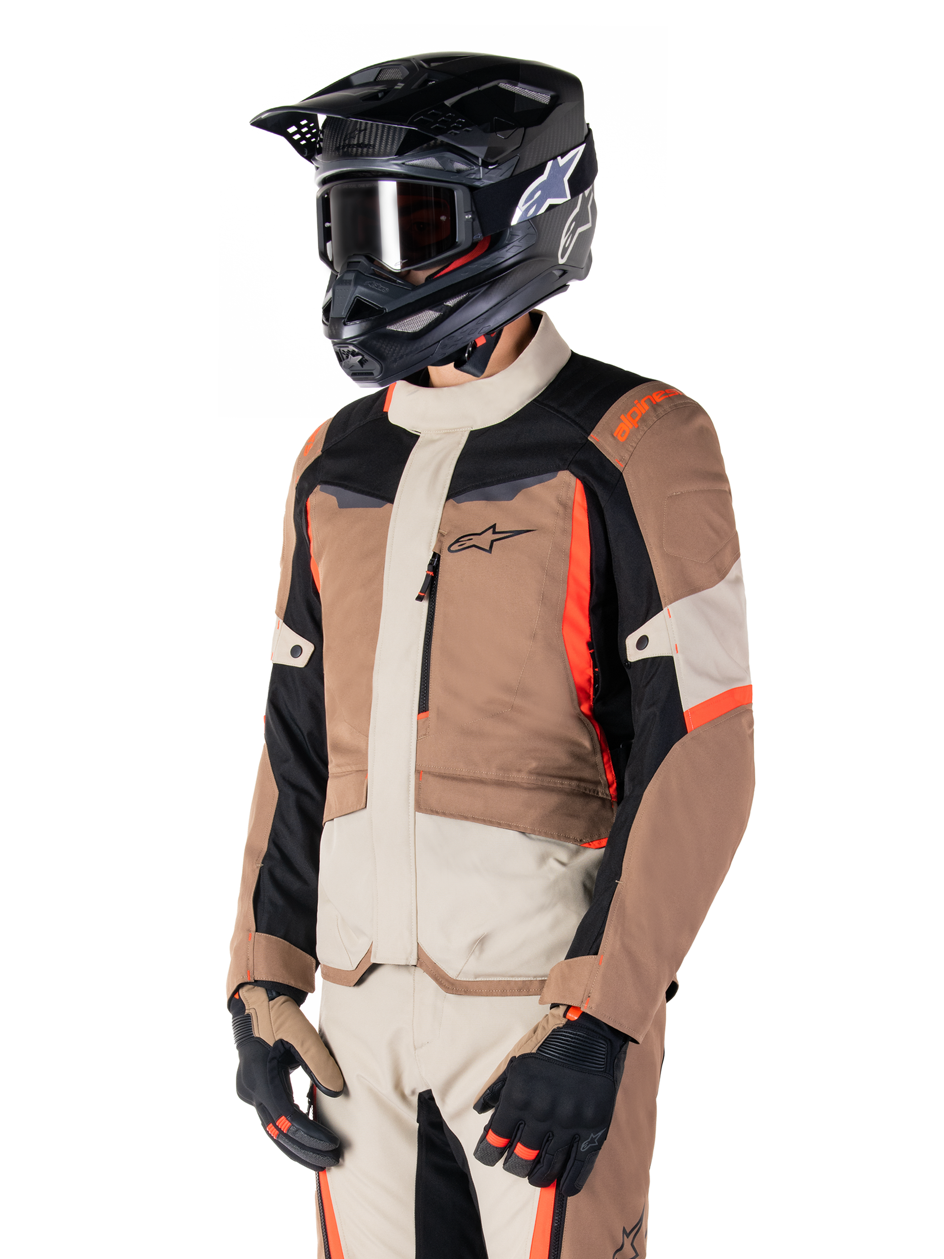 Giacca Alpinestars ST-1 Waterproof, giacca adventure touring, Dark Khaki Sand nero e rosso fluo, indossata da un pilota con casco da motocross nero e occhiali, caratterizzata da un design a pannelli con tasche cargo e branding Alpinestars sul petto