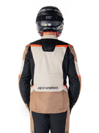Giacca impermeabile Alpinestars ST-1, Dark Khaki Sand Black Red Fluo, vista posteriore, giacca da moto adventure touring con ampio pannello posteriore sabbia, maniche nere e accenti rosso fluorescente, indossata da un pilota con casco nero