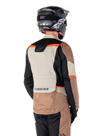 Giacca Alpinestars ST-1 Waterproof, giacca adventure touring, Dark Khaki Sand Black Red Fluo, vista posteriore con pannelli in tessuto a blocchi di colore, dettagli rosso fluorescente e marchio Alpinestars sulla parte inferiore della schiena, indossata da un pilota con casco nero