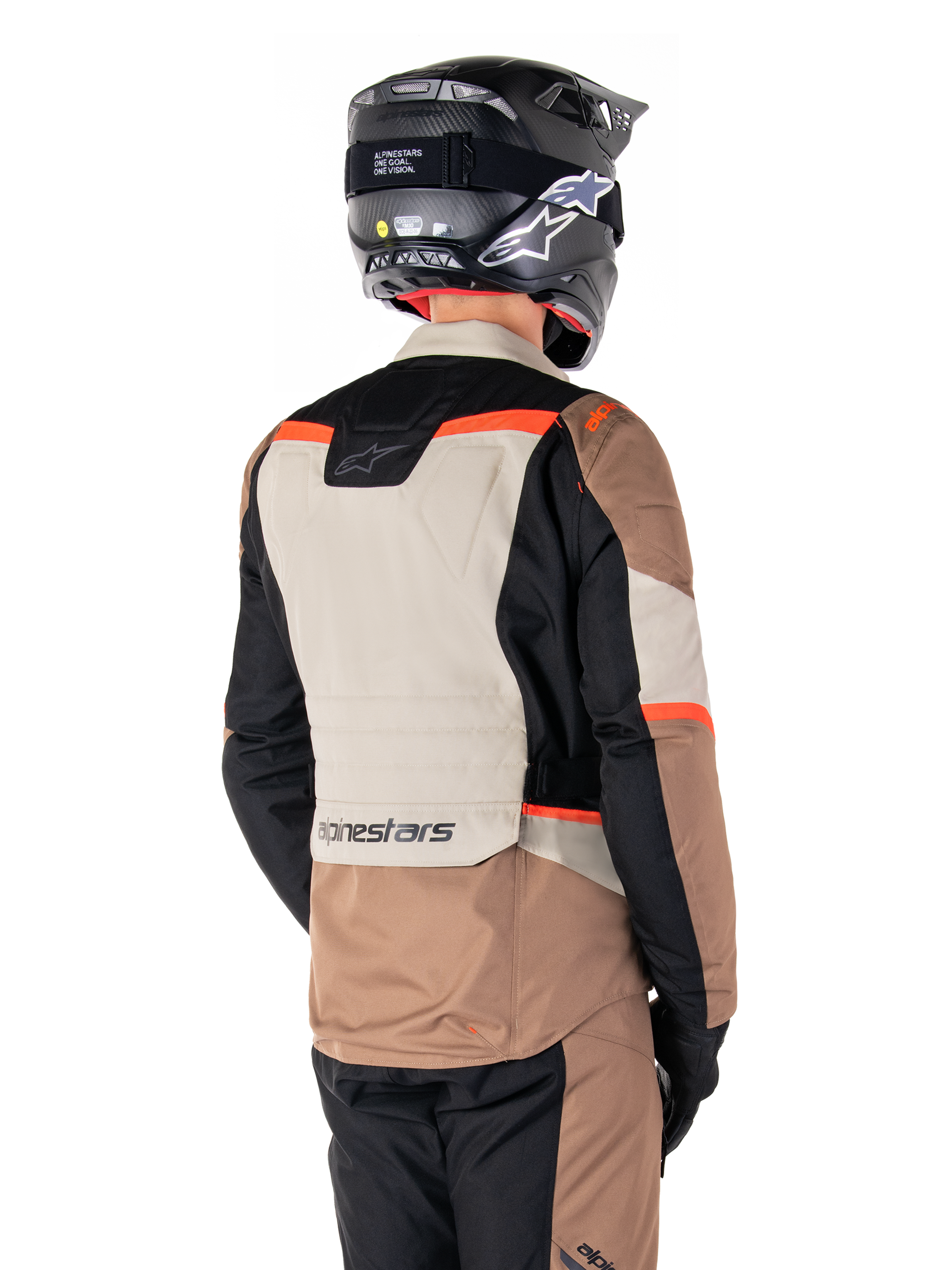 Giacca Alpinestars ST-1 Waterproof, giacca adventure touring, Dark Khaki Sand Black Red Fluo, vista posteriore con pannelli in tessuto a blocchi di colore, dettagli rosso fluorescente e marchio Alpinestars sulla parte inferiore della schiena, indossata da un pilota con casco nero