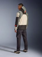 Alpinestars Giacca Mospher WP in Fur Gray Black Ice, vista posteriore di un modello che indossa un parka da moto tattico con pannelli crema, grigi e neri, dettagli rossi e cappuccio, abbinato a pantaloni cargo neri e stivali tecnici