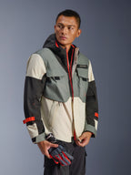 Giacca Alpinestars Mospher Waterproof in Fur Gray Black Ice, parka in tessuto multi-pannello grigio, nero e bianco sporco, dettagli rosso vivace su cerniere e cinturini, design d'ispirazione tattica con cappuccio e tasche multiuso, indossata da un modello con guanti da moto