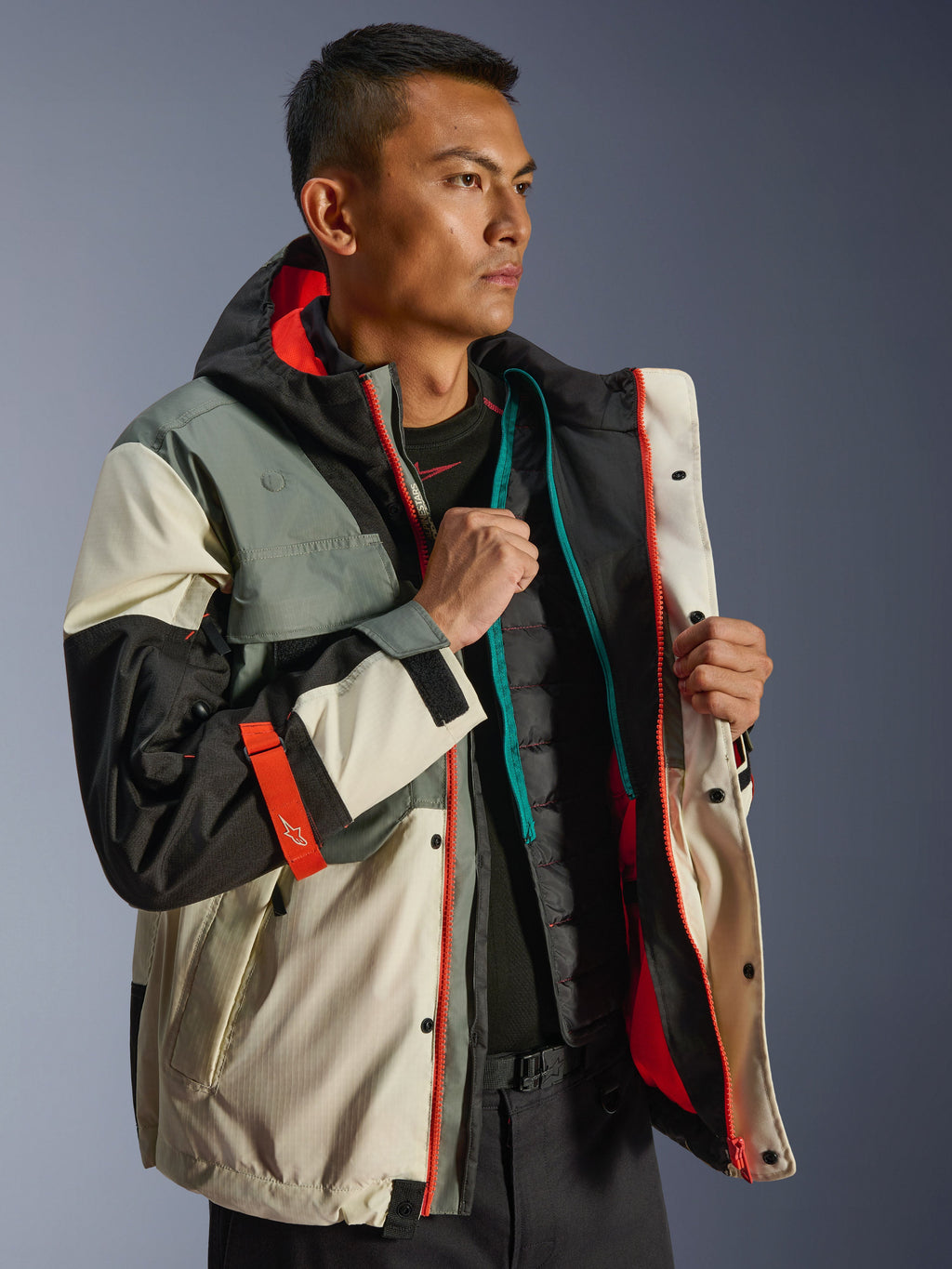 Giacca Alpinestars Mospher Waterproof, parka da moto urbano, Fur Gray Black Ice, con pannelli color crema e grigi e vivaci dettagli arancioni, mostrata aperta con un gilet termico trapuntato, design d'ispirazione tattica per la guida in ogni condizione climatica