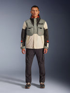 Giacca Alpinestars Mospher Waterproof in Fur Gray Black Ice, parka da moto in stile tattico indossato da un modello con pantaloni cargo scuri, design multitasche con pannelli a blocchi di colore grigio, crema e nero, abbigliamento da moto per pendolari urbani