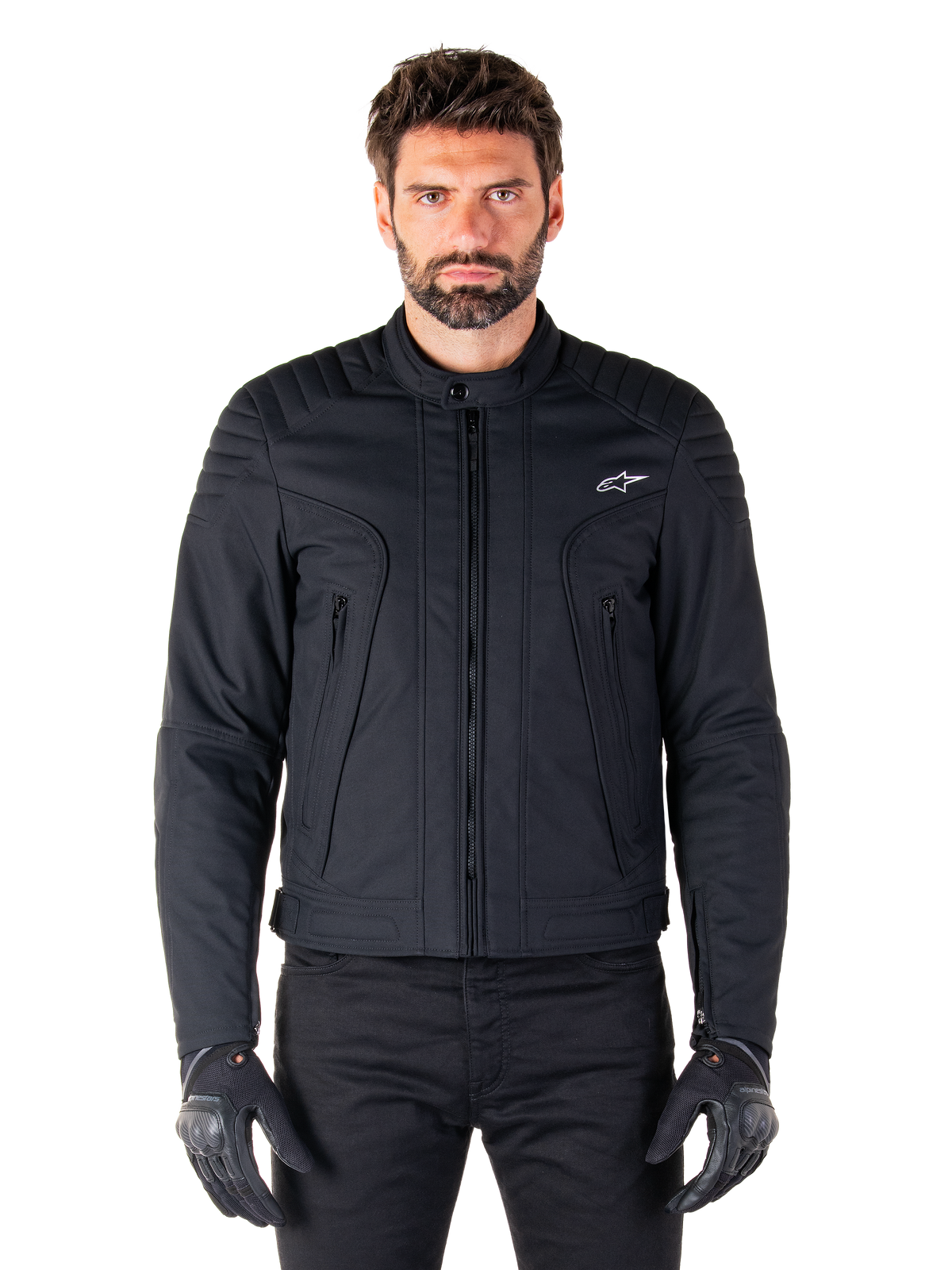 Giacca Alpinestars Clayton WR, giacca da moto nera, indossata da un modello, con dettagli trapuntati sulle spalle e grafiche tecniche, cerniera Vislon centrale, tasche verticali con zip, piccolo logo bianco sul petto, abbigliamento da guida urbana per uso stradale