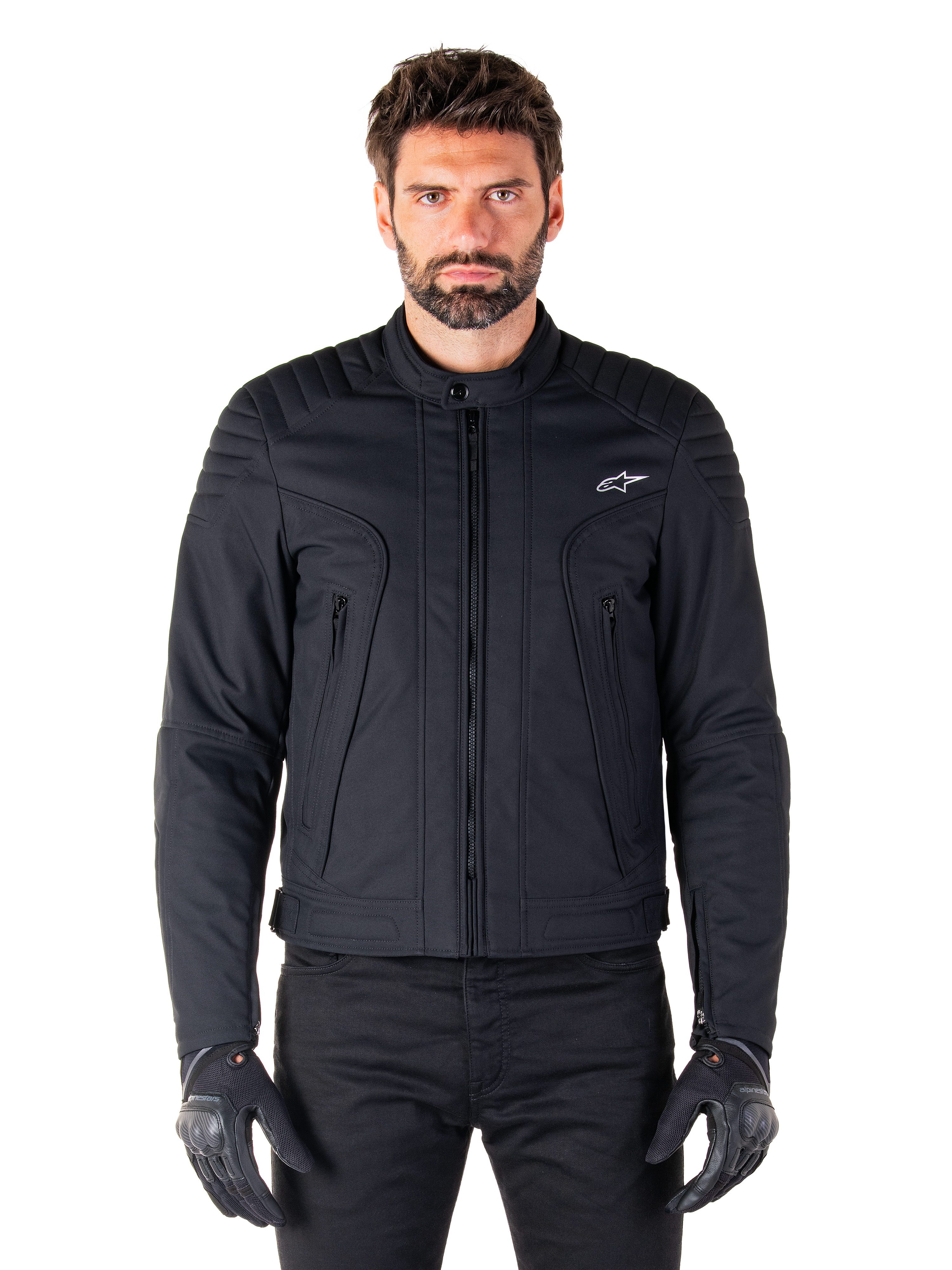 Giacca Alpinestars Clayton WR, giacca da moto nera, indossata da un modello, con dettagli trapuntati sulle spalle e grafiche tecniche, cerniera Vislon centrale, tasche verticali con zip, piccolo logo bianco sul petto, abbigliamento da guida urbana per uso stradale