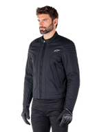 Alpinestars Clayton WR Jacket, nero, giacca da moto urbana in tessuto con dettagli trapuntati su spalle e avambracci, design slim-fit, finitura opaca, indossata da un pilota con guanti neri
