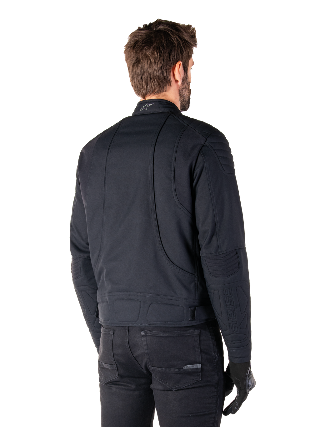 Giacca Alpinestars Clayton WR in nero, vista posteriore di tre quarti su un modello maschile, giacca da moto urbana con imbottitura trapuntata su spalle e gomiti, linee di cucitura tecniche e logo riflettente sul colletto, abbinata a pantaloni e guanti neri.