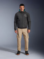 Giacca Alpinestars Moblast Waterproof, felpa da moto urbana nera con interno del cappuccio verde acqua, indossata con pantaloni cargo beige e stivali alti neri, abbigliamento da moto contemporaneo per tutte le stagioni