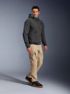 Modello che indossa la Giacca Alpinestars Moblast Waterproof in nero, felpa da moto urbana con cappuccio con fodera color ottanio, abbinata a pantaloni cargo kaki e sneakers nere, design moderno e minimalista in tessuto tecnico elasticizzato per il commuting in ogni condizione atmosferica