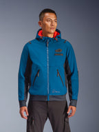 Alpinestars Moblast Waterproof Jacket indossata da un modello, blu e blu navy, giacca da moto urban riding, design con cappuccio e interno rosso, cerniere nere e dettaglio patch sul petto, abbigliamento da moto ispirato allo streetwear