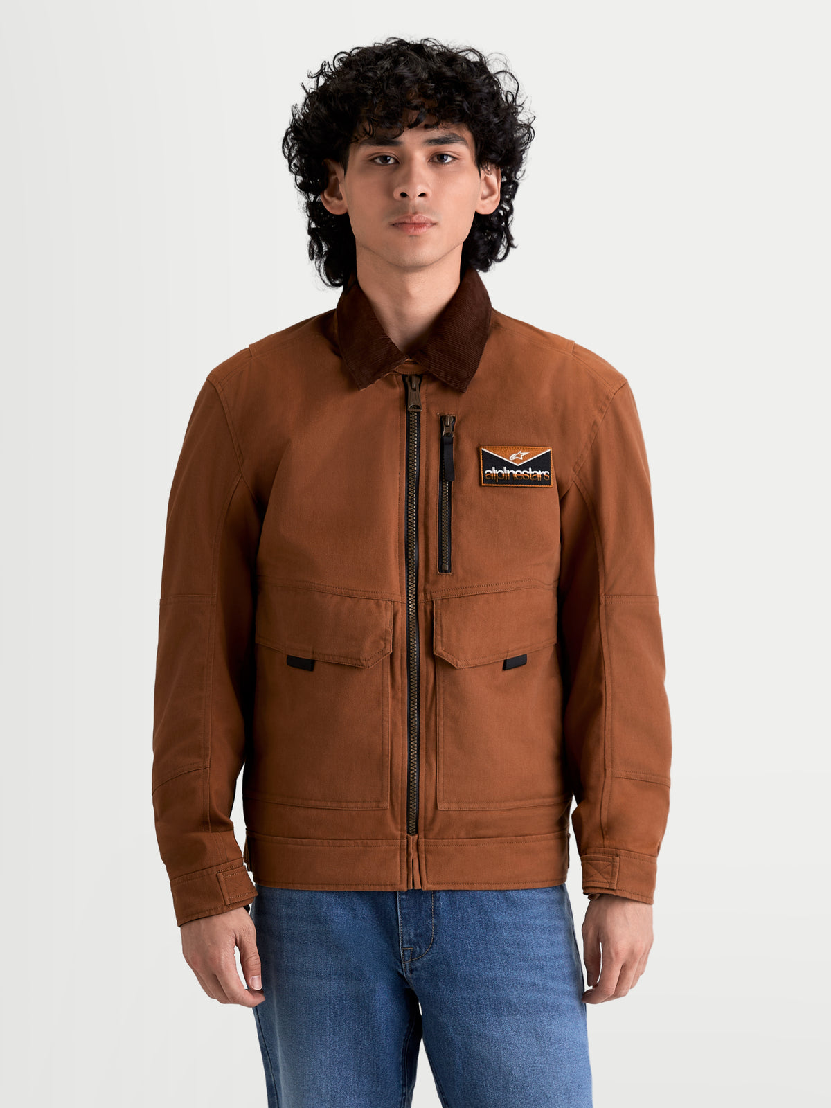 Alpinestars Mustang Wp Giacca, giacca da moto urbana contemporanea da uomo in ruggine scuro e marrone scuro, vista frontale su un modello che indossa abbigliamento da equitazione in stile workwear con colletto in velluto a coste