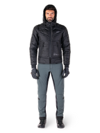 Giacca impermeabile Alpinestars Mohobbs in nero, modello che indossa un bomber trapuntato e imbottito con cappuccio, abbinato a pantaloni da moto grigi, guanti e stivali neri, abbigliamento da moto urban contemporary