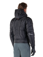Alpinestars Mohobbs Waterproof Jacket, nero, vista posteriore con costruzione trapuntata imbottita, cappuccio, marchio astars verticale sulla schiena e logo Alpinestars sulle maniche, indossata con pantaloni grigi e guanti neri