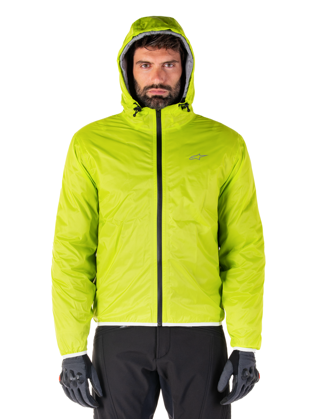 Giacca Alpinestars Mohobbs Waterproof, copertura antipioggia ripiegabile Lime Punch, guscio con cappuccio verde lime brillante indossato con pantaloni da moto neri e guanti da moto grigi, stile urban moto-streetwear