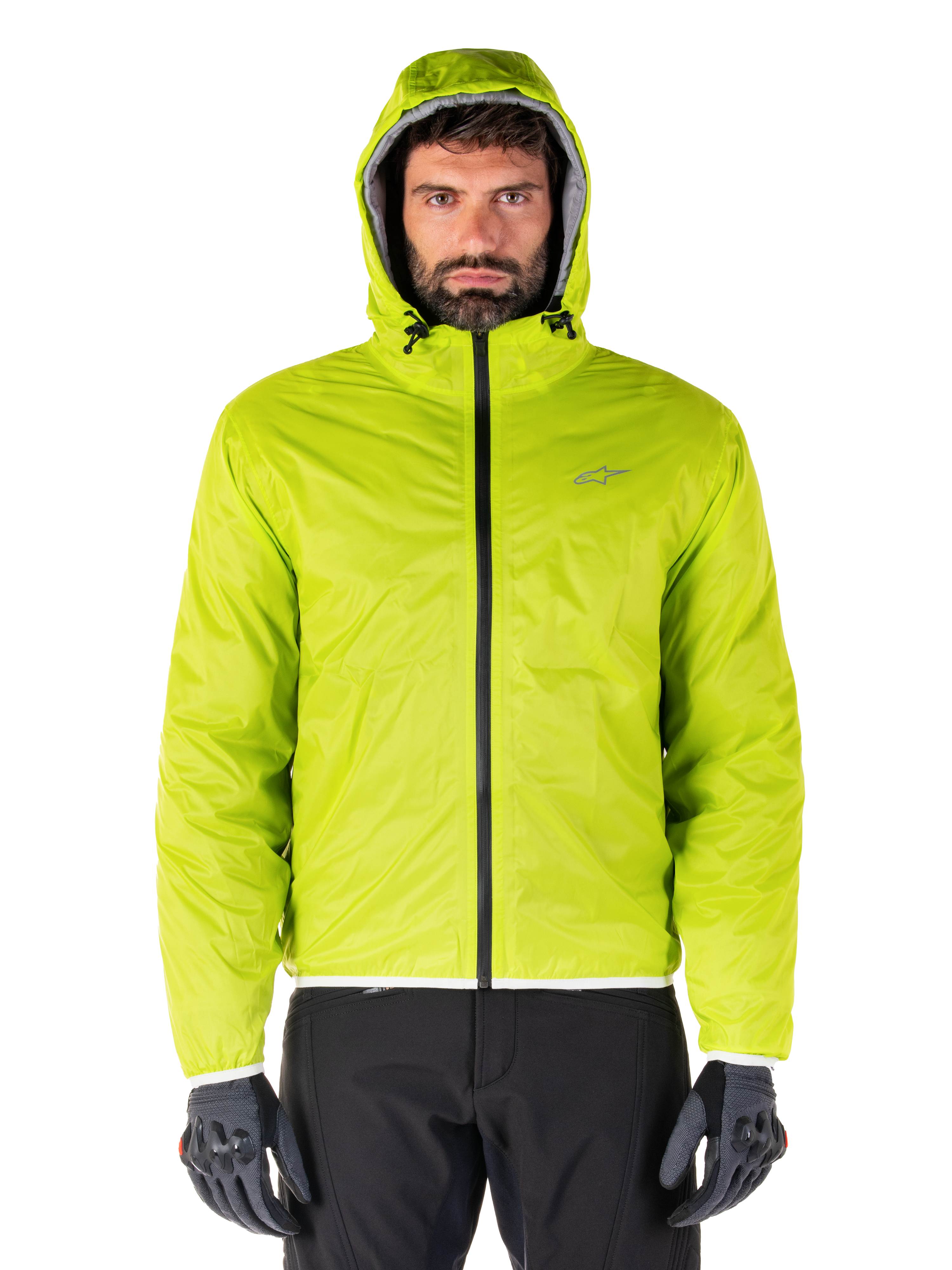 Giacca Alpinestars Mohobbs Waterproof, copertura antipioggia ripiegabile Lime Punch, guscio con cappuccio verde lime brillante indossato con pantaloni da moto neri e guanti da moto grigi, stile urban moto-streetwear