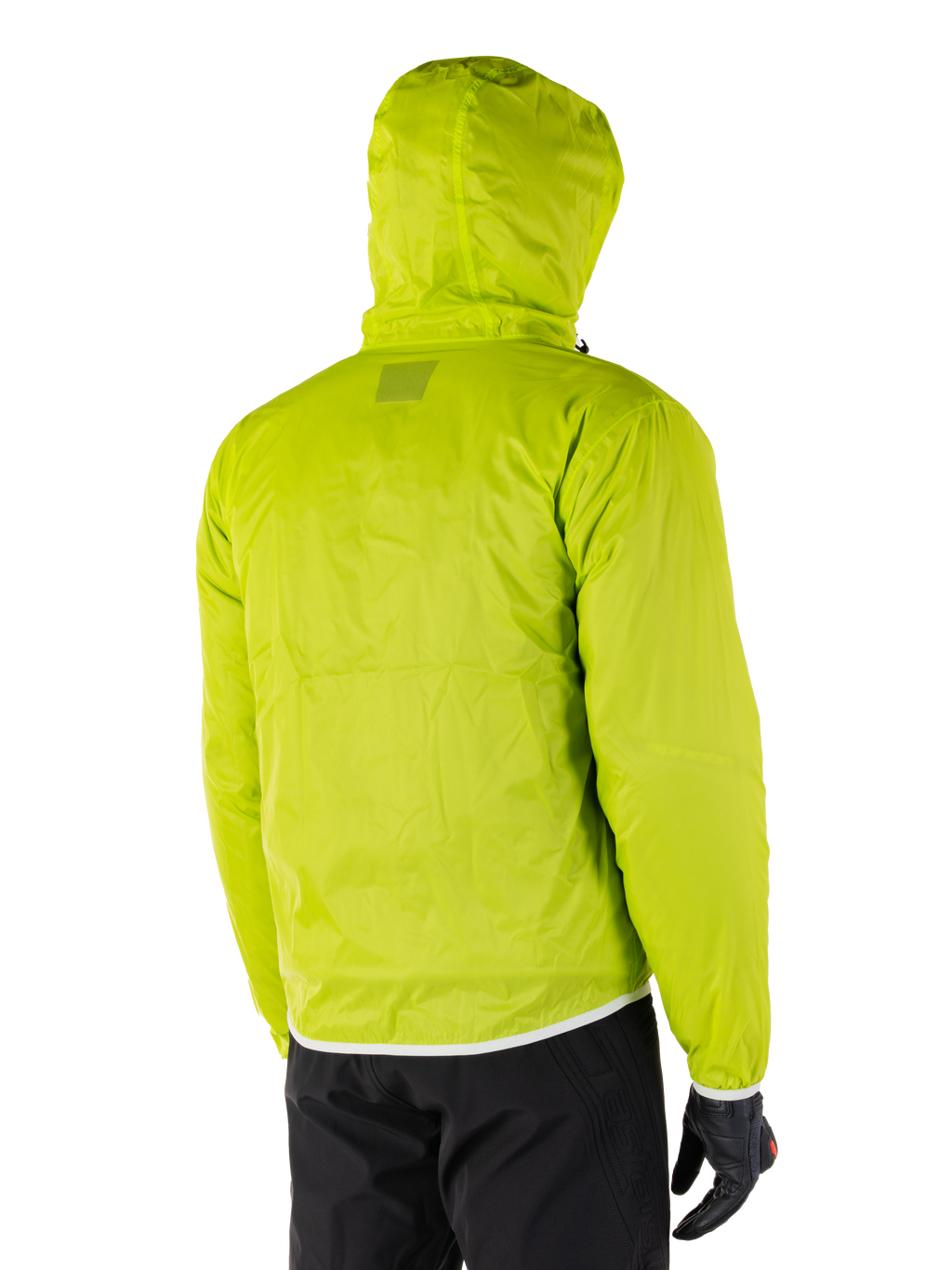 Alpinestars Mohobbs Waterproof Jacket, fodera antipioggia ripiegabile in Lime Punch, vista posteriore dello strato impermeabile verde neon con cappuccio, indossata con pantaloni da moto e guanti neri