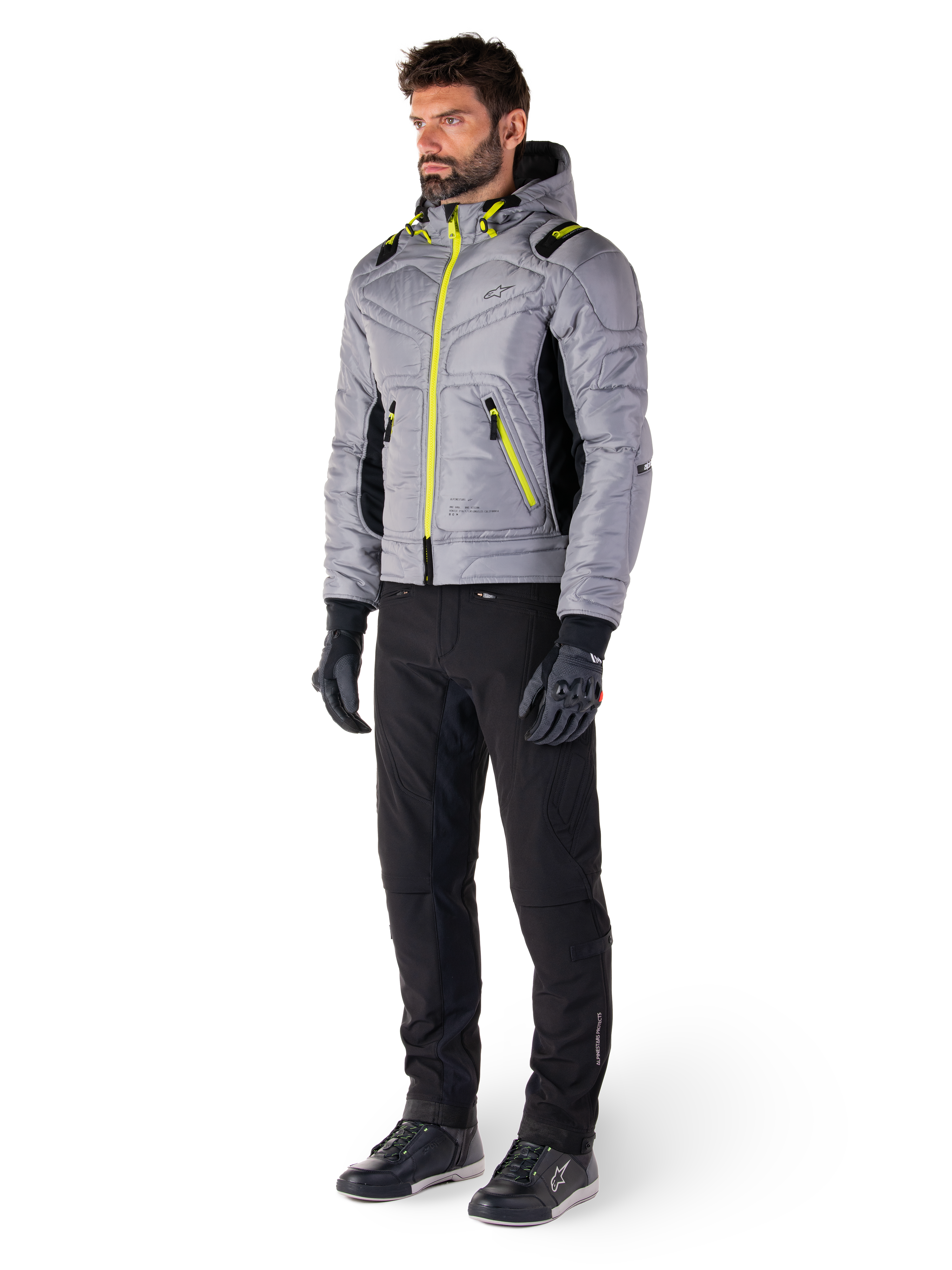Giacca Alpinestars Mohobbs Waterproof in Lunar Gray e Lime Punch, giacca da moto trapuntata stile bomber con accenti neon, indossata da un modello con pantaloni da guida e guanti neri, abbigliamento protettivo ispirato allo streetwear urbano