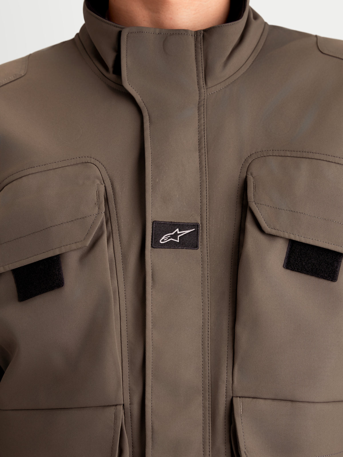 Alpinestars Altan Drystar Giacca, giacca da moto urbana contemporanea da uomo, colore marrone noce, vista in primo piano che mostra la costruzione in tessuto polyfabric, le tasche cargo a doppia entrata e il collo caldo integrato