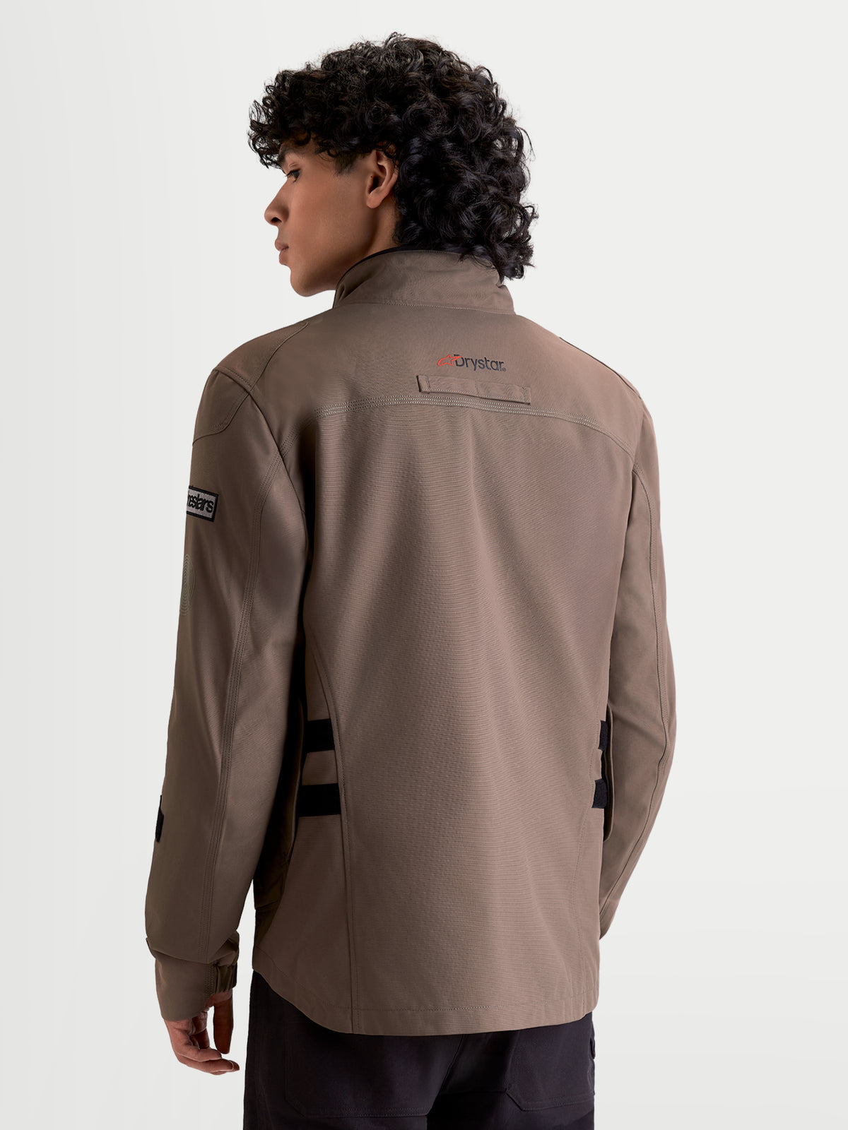 Alpinestars Altan Drystar Giacca, giacca da moto urbana contemporanea da uomo in marrone noce e nero, vista posteriore su un modello che mostra la silhouette stile field jacket e il marchio Drystar