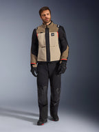 Modello con giacca Alpinestars Andes Pro Drystar® XF in Walnut Aluminum, giacca da touring adventure marrone e nera con accenti rossi, abbinata a pantaloni da moto, guanti e stivali neri, scatto in studio a figura intera per abbigliamento protettivo.