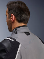 Giacca Alpinestars Andes Pro Drystar® XF, grigio scuro e nero, primo piano del colletto posteriore e della parte superiore della spalla, mostra il logo Tech-Air® Ready, la regolazione con cordino elastico e il logo a stella Alpinestars in tinta su tessuto tecnico