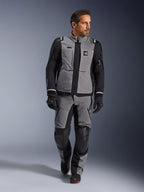 Modello che indossa la giacca Alpinestars Andes Pro Drystar® XF in grigio scuro e nero, completo da moto adventure con pantaloni e guanti coordinati, guscio in tessuto tecnico con marchio 'All Terra', equipaggiamento completo per il touring adventure a lunga distanza
