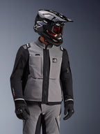 Giacca Alpinestars Andes Pro Drystar® XF, grigio scuro e nero, giacca da moto adventure indossata con casco SM10 nero e abbigliamento tecnico coordinato, design in tessuto a 3 strati con cerniera centrale e tasche sul petto, design articolato per il touring in ogni condizione climatica.