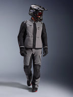 Motociclista adventure con giacca Alpinestars Andes Pro Drystar® XF in grigio scuro e nero, pantaloni adventure coordinati, casco Alpinestars nero con maschera, guanti e stivali neri, abbigliamento tecnico da touring completo per lunghi viaggi