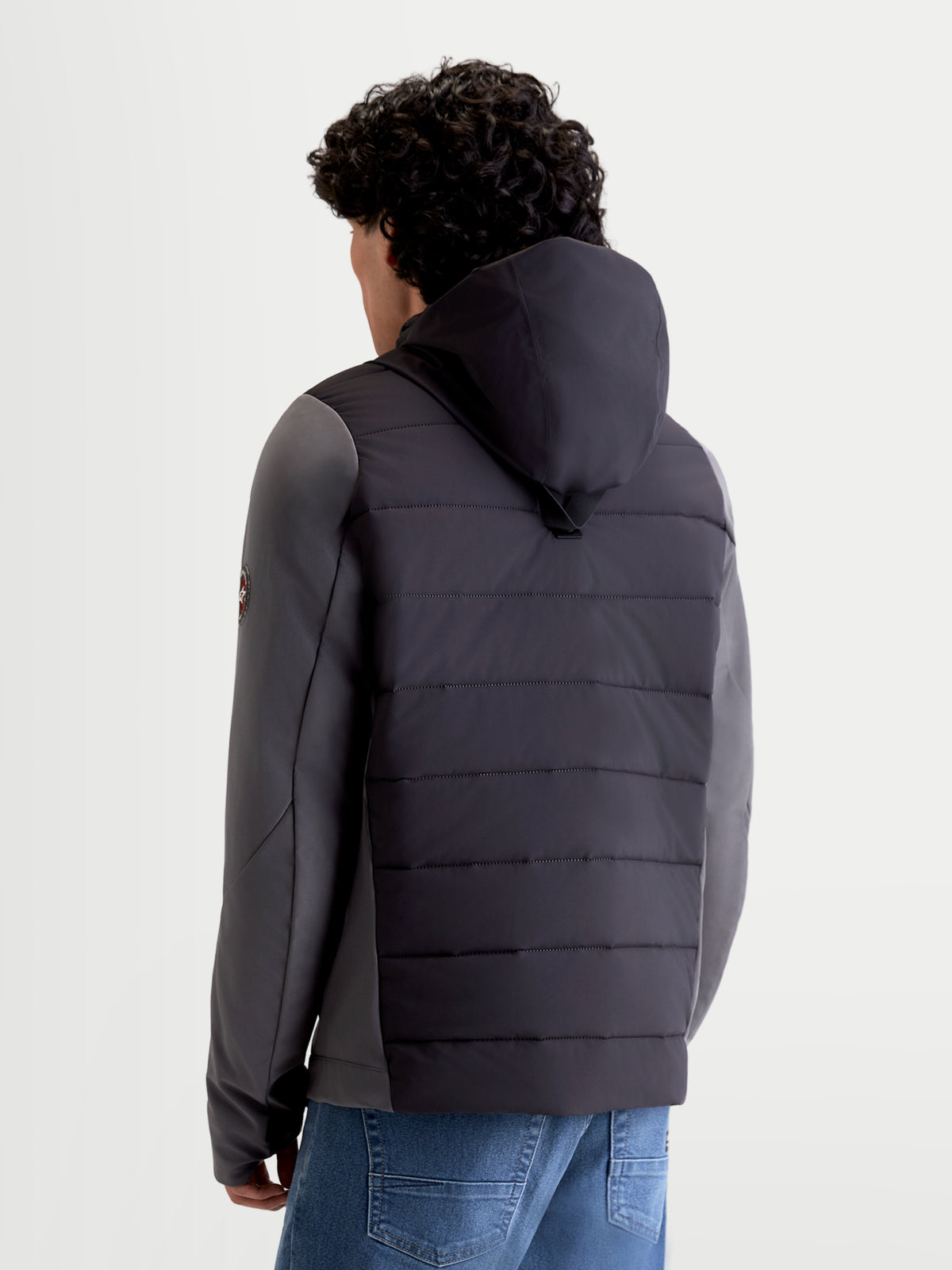 Alpinestars Therma-Tech Waterproof Jacket, giacca da moto urbana da uomo in nero e grigio scuro, vista posteriore su un modello che mostra il sistema di cappuccio integrato e la costruzione trapuntata