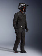 Giacca Alpinestars Cusco Drystar®, giacca da moto adventure touring nera, indossata con pantaloni neri coordinati e casco integrale con occhiali, caratterizzata da un design multi-tasca funzionale, costruzione in tessuto tecnico e logo Drystar sulla manica.