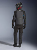 Giacca Alpinestars Cusco Drystar®, nero e grigio scuro, vista posteriore del pilota con abbigliamento adventure touring completo, ampio pannello posteriore grigio con logo Alpinestars, dettagli blu sulle maniche, abbinata a pantaloni neri e casco.