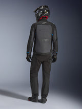 Giacca Alpinestars Cusco Drystar®, nero e grigio scuro, vista posteriore del pilota con abbigliamento adventure touring completo, ampio pannello posteriore grigio con logo Alpinestars, dettagli blu sulle maniche, abbinata a pantaloni neri e casco.