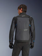 Giacca Alpinestars Cusco Drystar®, giacca da moto, nero e grigio scuro, vista posteriore su un modello con ampio pannello posteriore grigio, logo Alpinestars bianco e accenti blu sulle maniche.