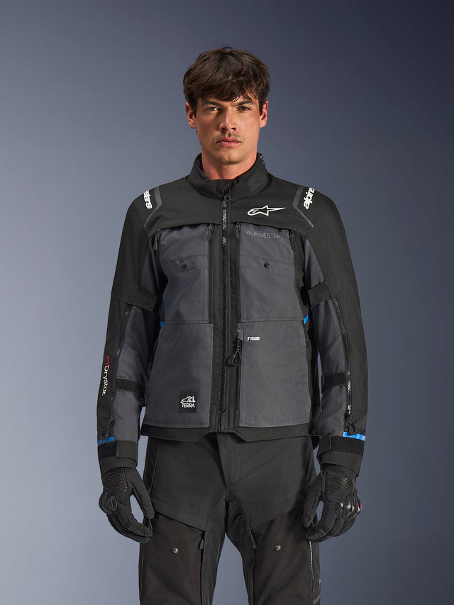 Giacca Alpinestars Cusco Drystar®, giacca da moto touring, nero e grigio scuro, vista frontale su modello, con loghi Alpinestars su petto e spalle, marchio Drystar® sulla manica, design tecnico multitasca con cerniere di ventilazione, abbinata ad abbigliamento tecnico nero