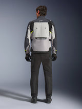 Vista posteriore di un motociclista che indossa la giacca Alpinestars Cusco Drystar® nei colori Ice Gray, Mid Gray e Deep Gray, abbinata a pantaloni e guanti da moto neri, che mette in risalto il grande pannello di ventilazione posteriore e il branding Alpinestars.