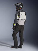 Giacca Alpinestars Cusco Drystar® in Ice Gray, Mid Gray e Deep Gray, vista posteriore su un pilota. Presenta accenti giallo fluorescente, ampio pannello di ventilazione posteriore con branding e costruzione in tessuto resistente. Indossata con pantaloni da moto neri e un casco adventure per un look touring completo.