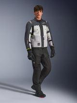 Giacca Alpinestars Cusco Drystar®, giacca da moto adventure, colori Ice Gray, Mid Gray e Deep Gray, indossata da un modello con pantaloni e guanti neri, pannelli grigi multi-tono in tessuto resistente, con prese d'aria con zip e logo Alpinestars, fotografia professionale in studio per abbigliamento da strada e adventure.