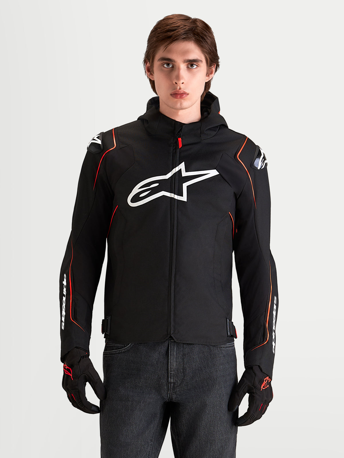 Alpinestars Zaca V 2 Waterproof Giacca, giacca da moto sportiva da uomo in nero e rosso fluo con protezioni spalle DFS e logo Astar bianco sul petto, indossata da un modello in uno studio