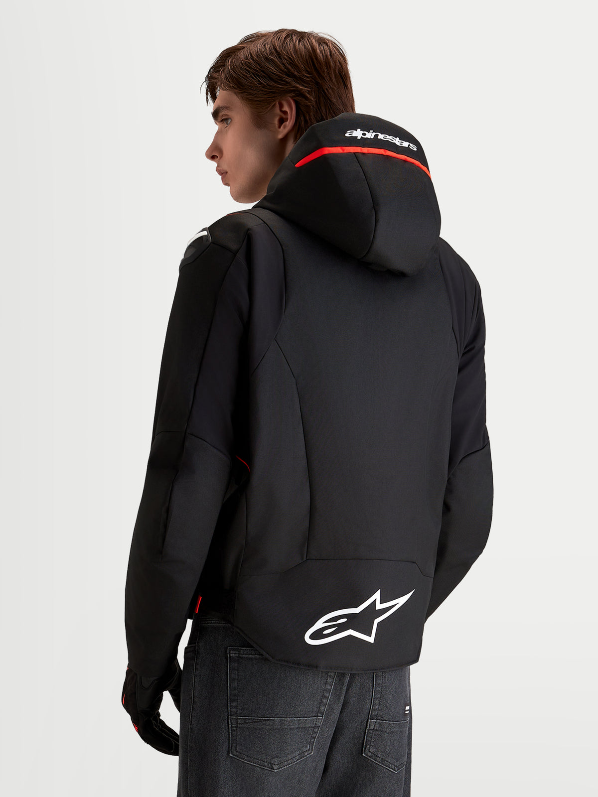 Alpinestars Zaca V 2 Waterproof Giacca, giacca da moto impermeabile da uomo, nero e rosso fluo, con cappuccio integrato e logo Astar bianco sul fondo posteriore, indossata da un modello, vista posteriore