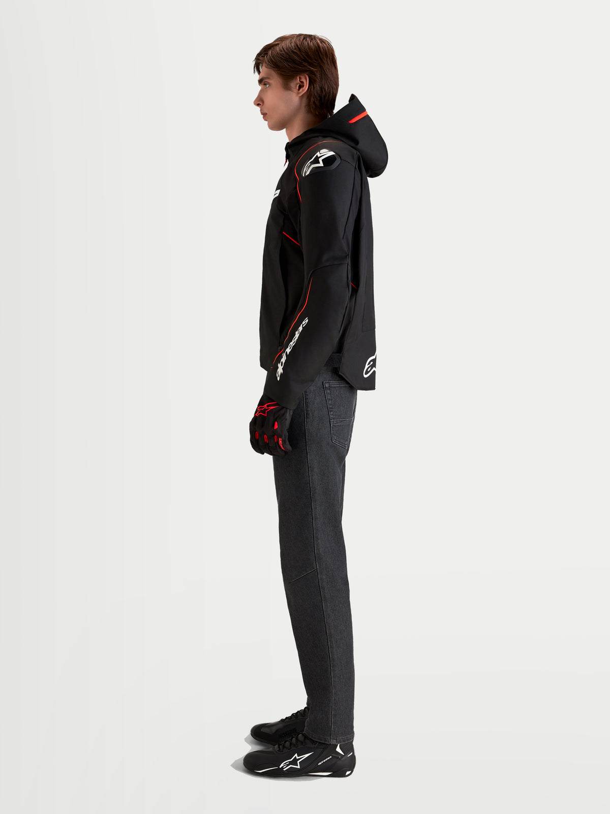 Alpinestars Zaca V 2 Waterproof Giacca, giacca da moto sportiva da uomo in nero e rosso fluo, con cappuccio integrato, protezioni spalle DFS e maniche precurvate, indossata da un modello di profilo