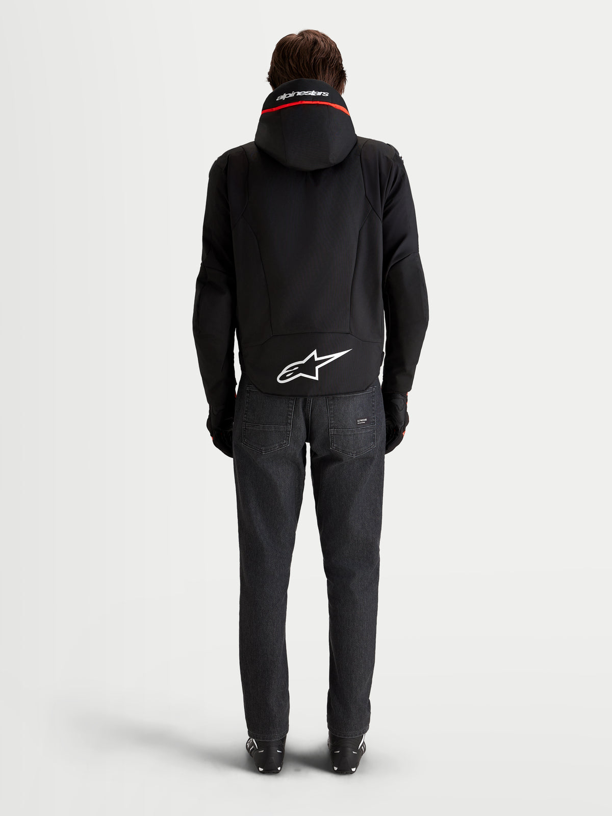 Alpinestars Zaca V 2 Waterproof Giacca, giacca da moto impermeabile da uomo, vista posteriore con cappuccio integrato, logo Astar bianco sul fondo e jeans in denim scuro, nero