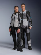 Uomo e donna con giacche Alpinestars Stella ST-2 Air e pantaloni tecnici coordinati, colorazione Ice Gray e Black con accenti blu, caratterizzati da ventilazione in mesh e marchio 'ALPINESTARS EXPLORATION EQUIPMENT', scatto di coppia in studio