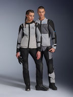 Modelli uomo e donna che indossano giacche Alpinestars ST-2 Air in Ice Gray, Dark Gray e Nero, abbigliamento tecnico da mototurismo estivo con ampi pannelli in rete e branding Exploration Equipment, abbinati a pantaloni, guanti e stivali da moto neri.
