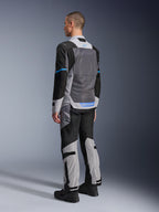 Modello maschile visto da dietro che indossa la giacca Alpinestars ST-2 Air in Ice Gray, Dark Gray e nero, con un ampio pannello posteriore in rete grigia, dettagli del logo blu e pantaloni da moto coordinati per il touring estivo.