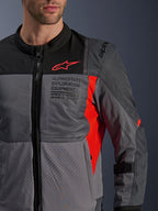 Giacca Alpinestars ST-2 Air, giacca da moto in tessuto, Deep Gray e Dark Gray con dettagli Bright Red, primo piano con pannelli in rete traspirante, tessuto traforato al laser e logo a stella rosso con marchio Alpinestars Exploration Equipment
